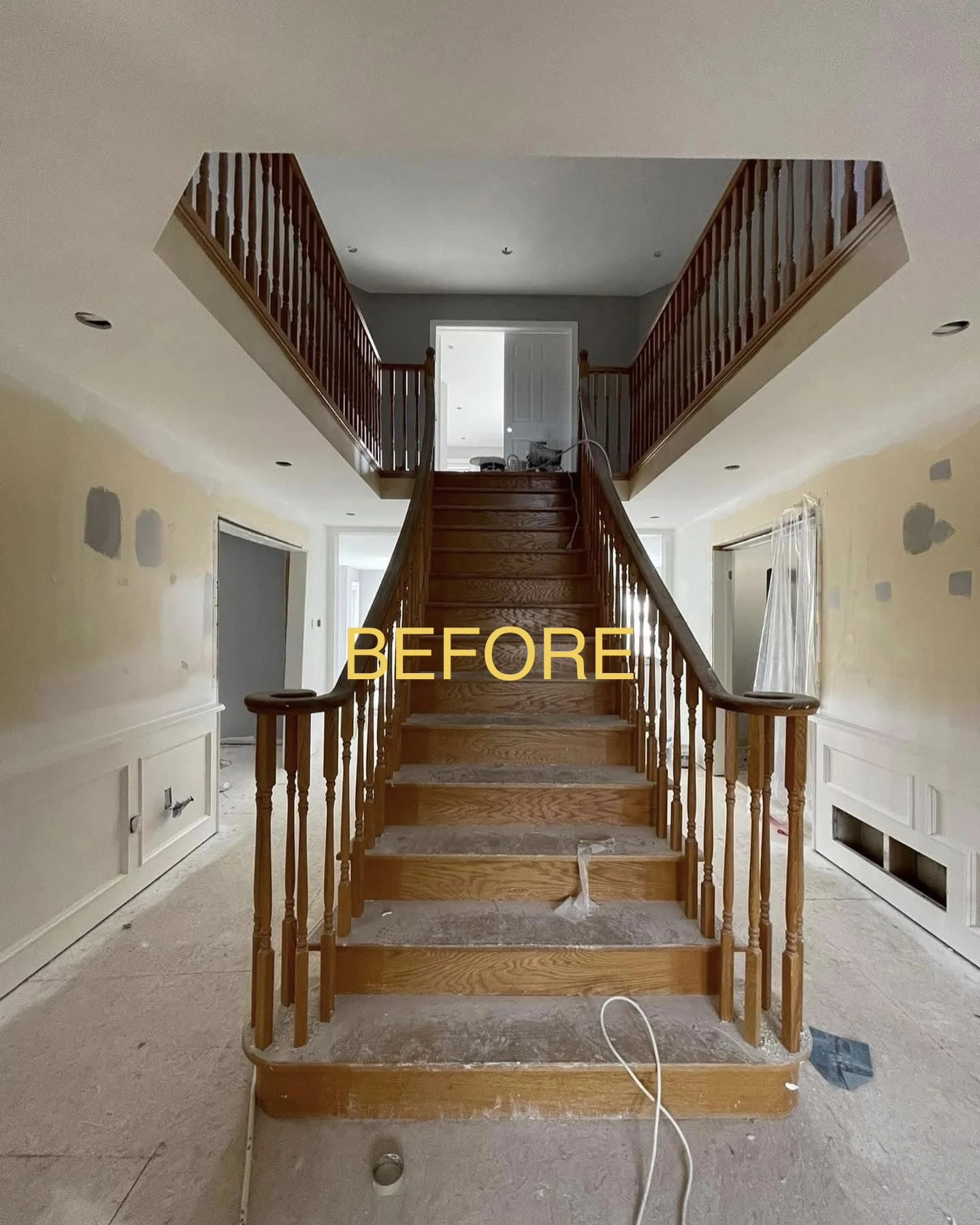 Grand two-story oak staircase before transformation showing natural wood treads and spindles