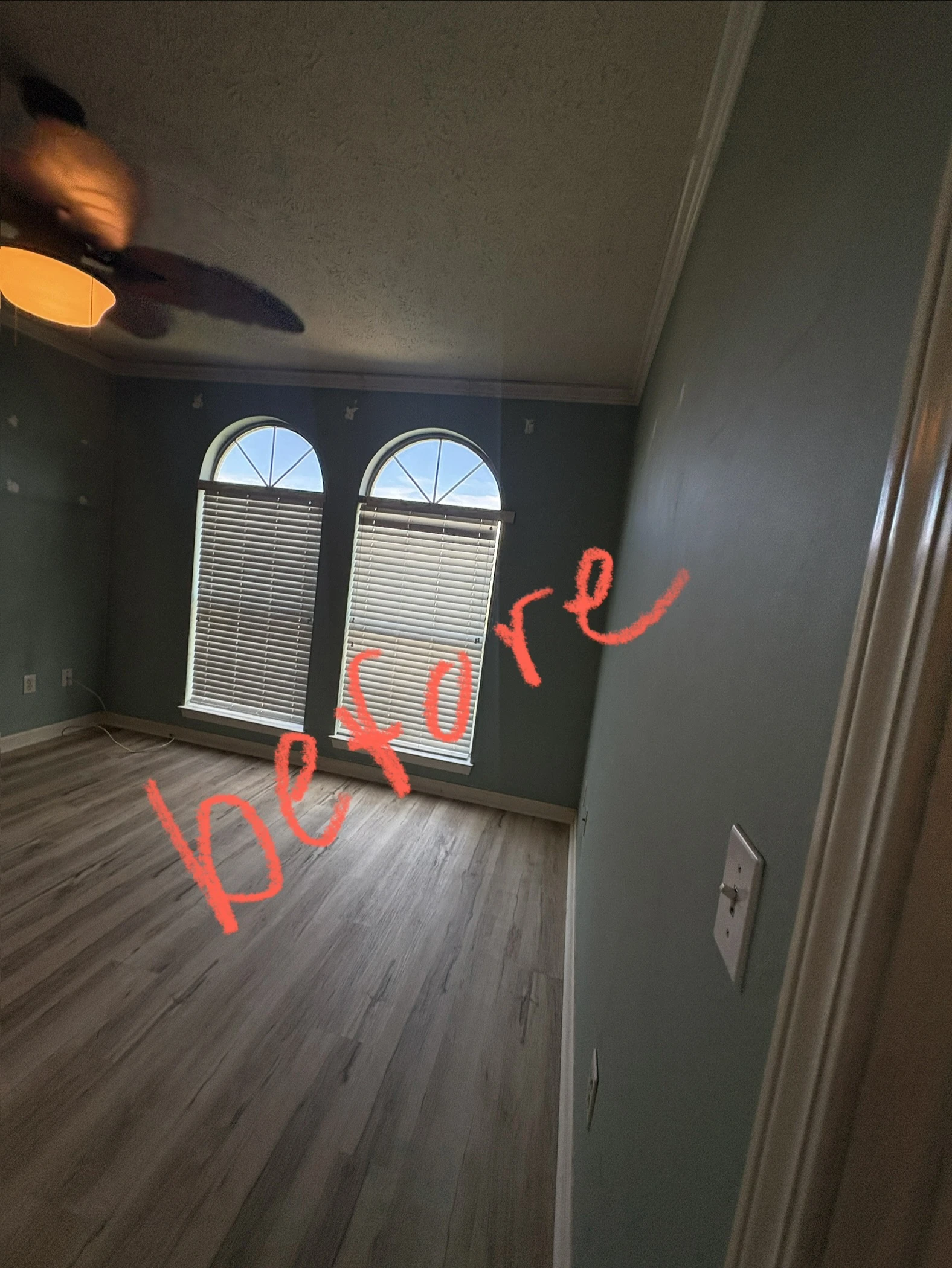 Bedroom with dark teal blue walls and arched windows before painting